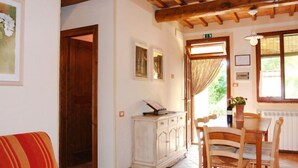 A cozy room with a wooden ceiling, a dining table with chairs, a white cabinet, and a door leading to another room. - Podere La Torre by Interhome (Certaldo)