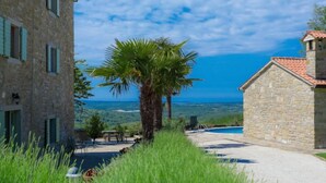 Ein Gebäude aus Stein mit einem Pool, umgeben von üppiger Vegetation und freiem Blick auf das Meer.