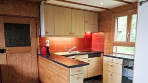 Une cuisine moderne avec des meubles en bois, un plan de travail noir et un pare-feu rouge.