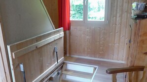Une pièce en bois avec un banc intégré, une fenêtre ornée de rideaux rouges et une étagère remplie de livres.