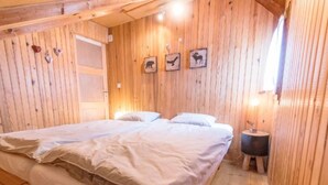 Une chambre dans une cabane en bois, avec un lit double, des murs en bois et des tableaux représentant des animaux.