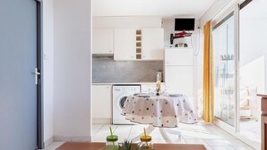 Une cuisine moderne avec des meubles blancs, un lave-linge et un coin repas avec une table mise pour deux personnes.