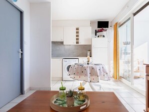 A modern kitchen with white cabinets, a washing machine, and a dining area with a table set for two.