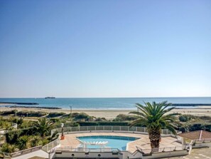 A pool area with a view of the beach and ocean.