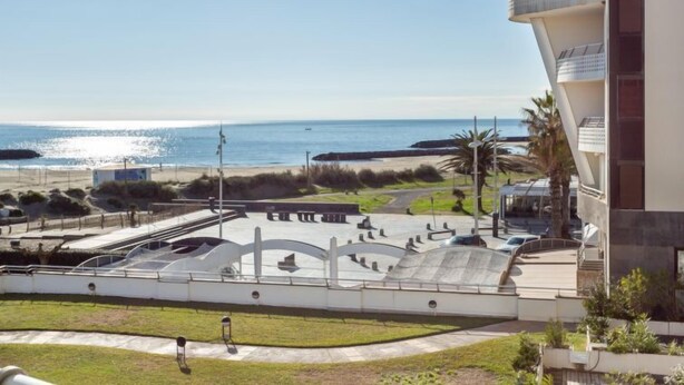 Une vue sur la côte, avec un bâtiment moderne, une plage et un parc à skate.
