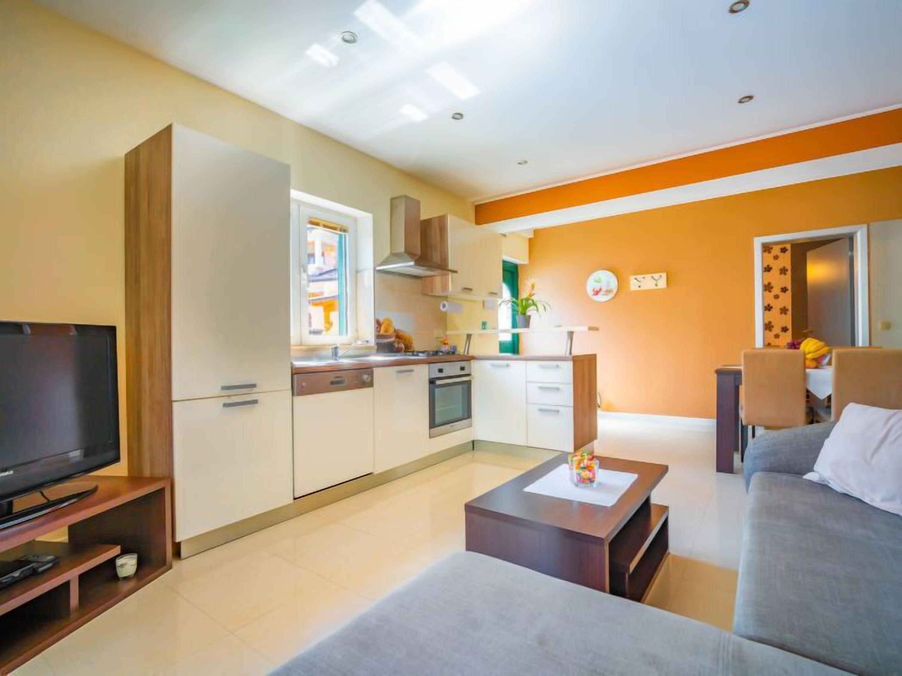 Ein modernes Wohnzimmer mit Flachbildfernseher, grauem Sofa und Couchtisch aus Holz.