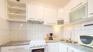 A modern kitchen with white cabinets, a built-in oven, a microwave, and a coffee maker.