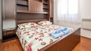 A bedroom with a bed, a wardrobe, a bedside table, and a window with curtains.