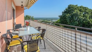 Un balcon avec une table et des chaises, un pot de fleurs et une vue sur le paysage.