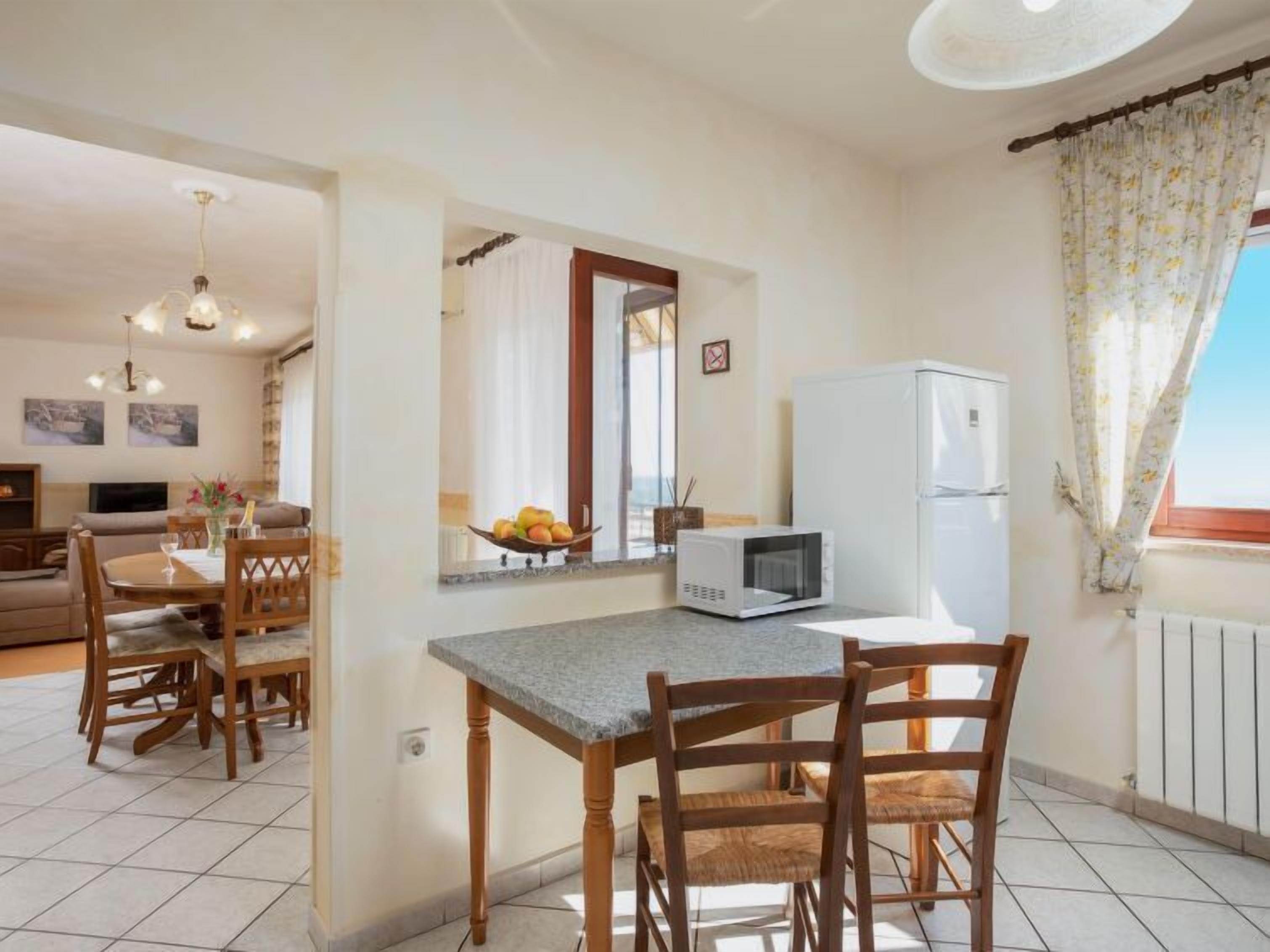 A compact kitchen with a dining area, a microwave, and a refrigerator.
