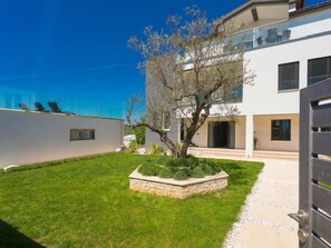 A modern two-story house with a well-maintained lawn and a stone planter with shrubs. - Apartment La Mer by Interhome (Pula)