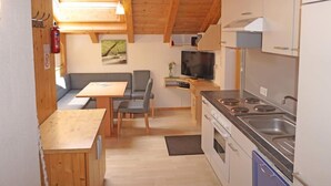 A compact kitchen with a stove, sink, and a small dining area with a table and chairs. - Frischmann by Interhome (Umhausen)