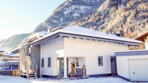 A modern two-story building with a flat roof, a covered entrance, and a small outdoor area with a ladder leading to the upper floor. - Frischmann by Interhome (Umhausen)