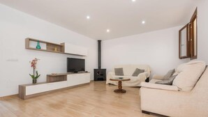 Een moderne woonkamer met een flatscreen televisie, een bank, een salontafel en een open haard.