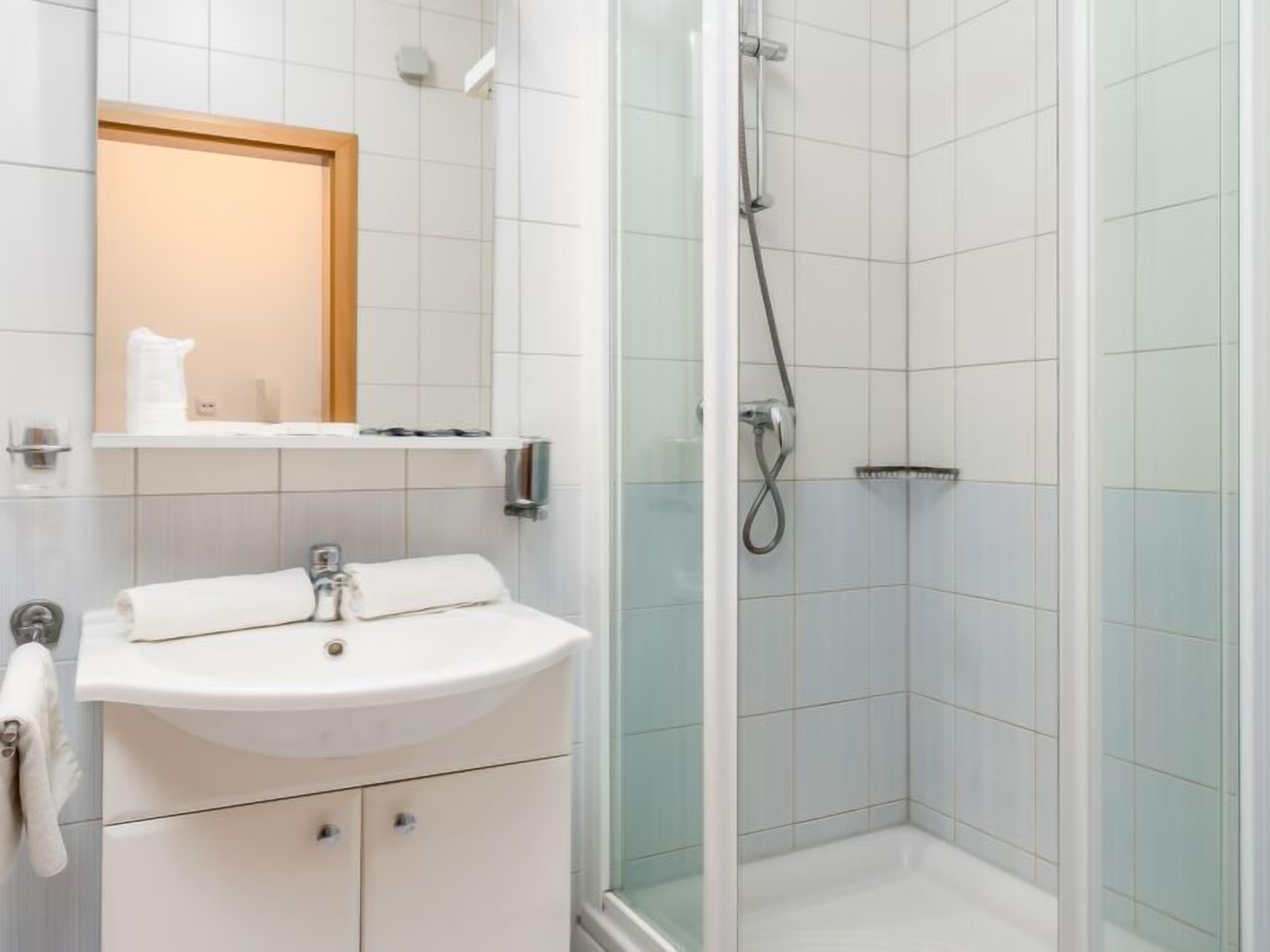A bathroom with a white sink, mirror, and shower.