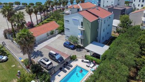 Un edificio residencial con piscina, rodeado de palmeras y vista al mar.