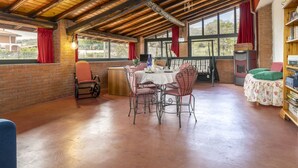 A rustic dining area with a wooden ceiling, brick walls, and large windows.