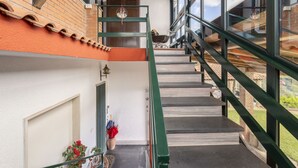 A staircase with green railings leading to a balcony with a view of the sky and a brick building.