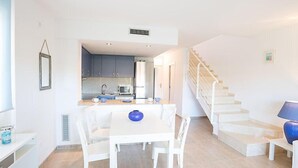 Una cocina moderna con armarios grises, una encimera blanca y un jarrón azul sobre la mesa.