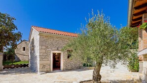 Un edificio de piedra con techo de tejas, una puerta y un árbol en una jardinera de piedra.