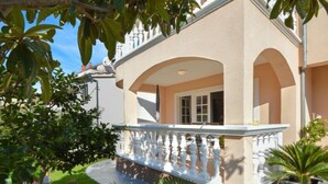 A two-story building with a balcony, arched windows, and a garden with potted plants. - Apartment Mladen by Interhome (Vodice)