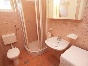 Ein Badezimmer mit Toilette, Duschkabine, Waschbecken und Spiegel.