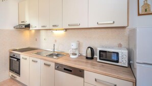 A modern kitchen with white cabinets, a stainless steel sink, a coffee maker, a microwave, and a dishwasher. - Apartment Mladen by Interhome (Vodice)