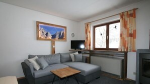A modern living room with a grey sectional sofa, a wooden coffee table, a television, and a fireplace. - Vacation home Amberg by Interhome (Schwoich)