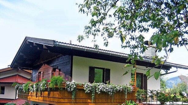 A two-story house with a balcony, surrounded by greenery and a mountain in the background. - Vacation home Amberg by Interhome (Schwoich)