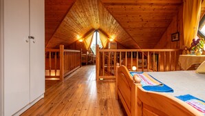 A cozy attic bedroom with wooden beams, a bed, a desk, and a window with curtains. - Modlinek by Interhome (Ustka)