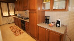 A kitchen with wooden cabinets, a microwave, a coffee maker, and a tiled backsplash. - Rondinelli by Interhome (Peschiera del Garda)