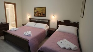 A hotel room with two beds, each with a wooden headboard and pink bedding. There are towels on each bed and a painting on the wall. - Rondinelli by Interhome (Peschiera del Garda)