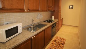 A kitchen with wooden cabinets, a granite countertop, a stainless steel sink, a microwave, a stove, and a dishwasher. - Rondinelli by Interhome (Peschiera del Garda)