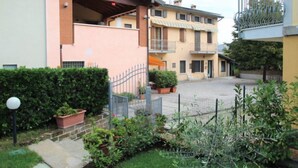 A residential building with a covered patio, a fenced courtyard, and potted plants. - Rondinelli by Interhome (Peschiera del Garda)