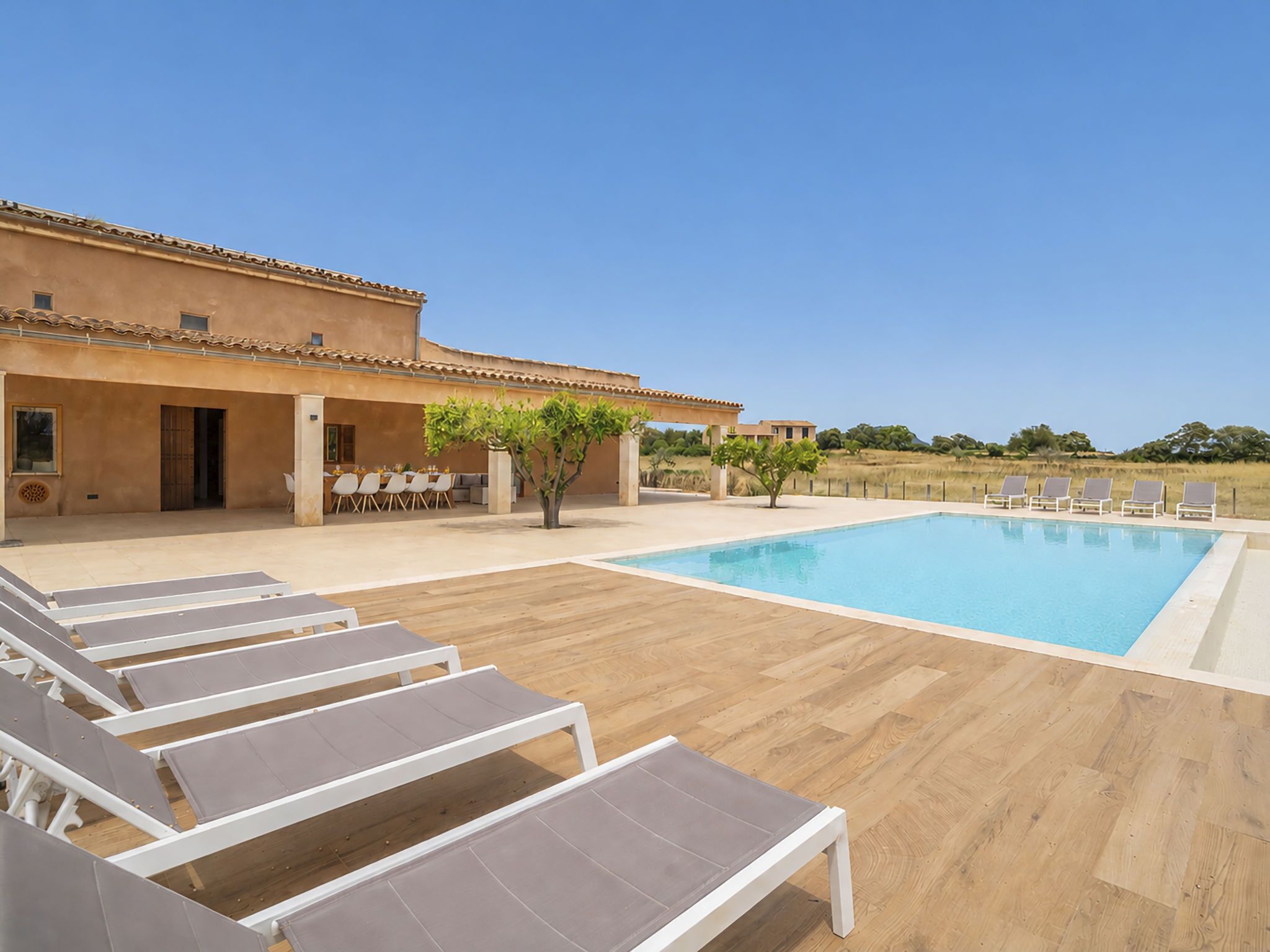 A poolside area with lounge chairs, a pool, and a building with a tiled roof.