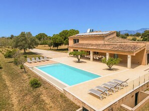 A villa with a swimming pool, outdoor seating, and a view of the mountains.