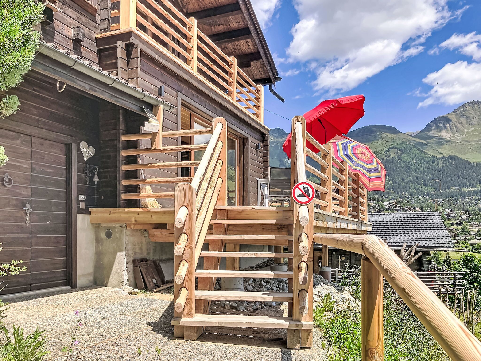 Un escalier en bois menant à un bâtiment d’où l’on a vue sur la montagne.
