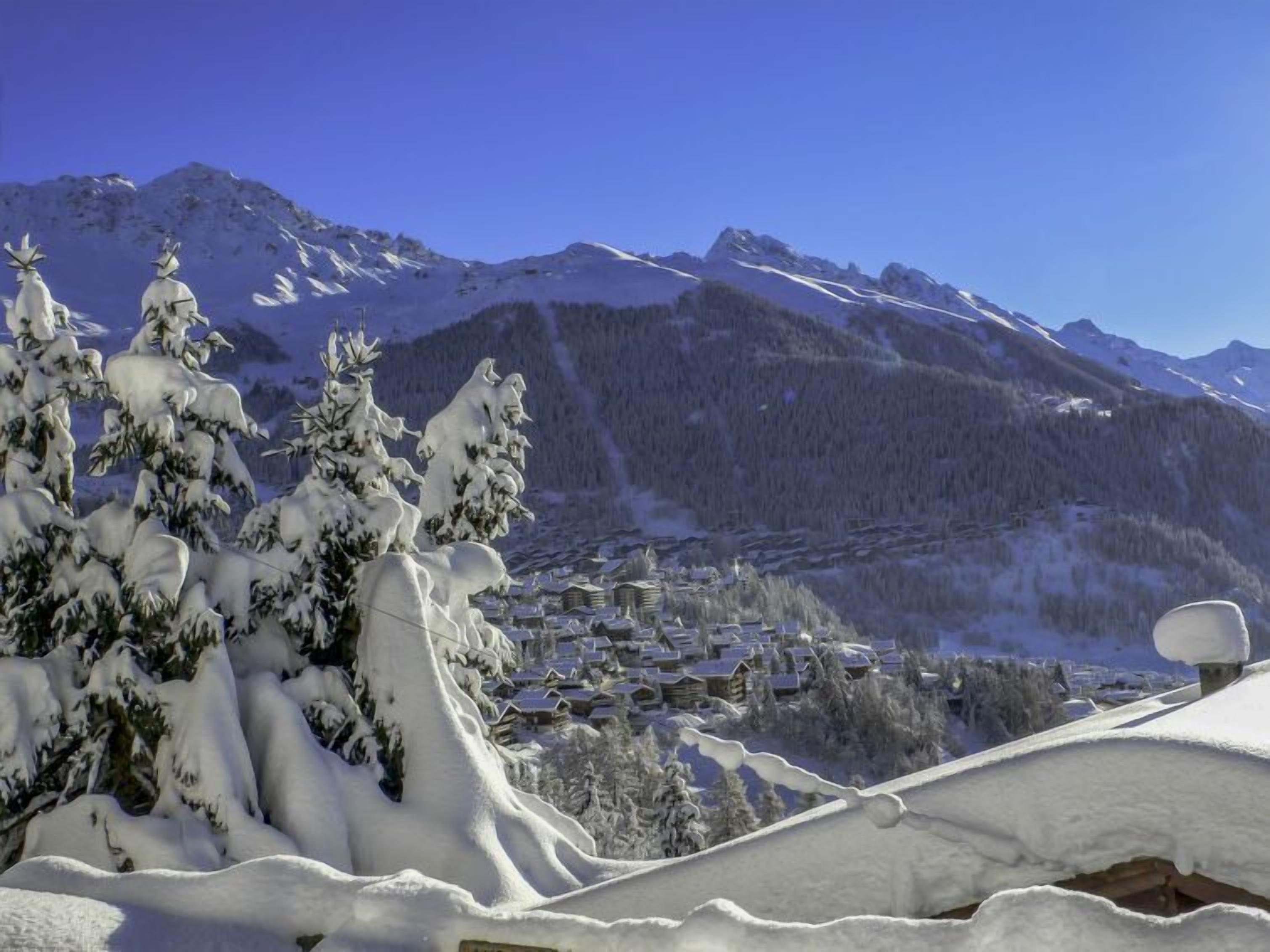 Un paisaje montañoso cubierto de nieve con un pueblo en las faldas.