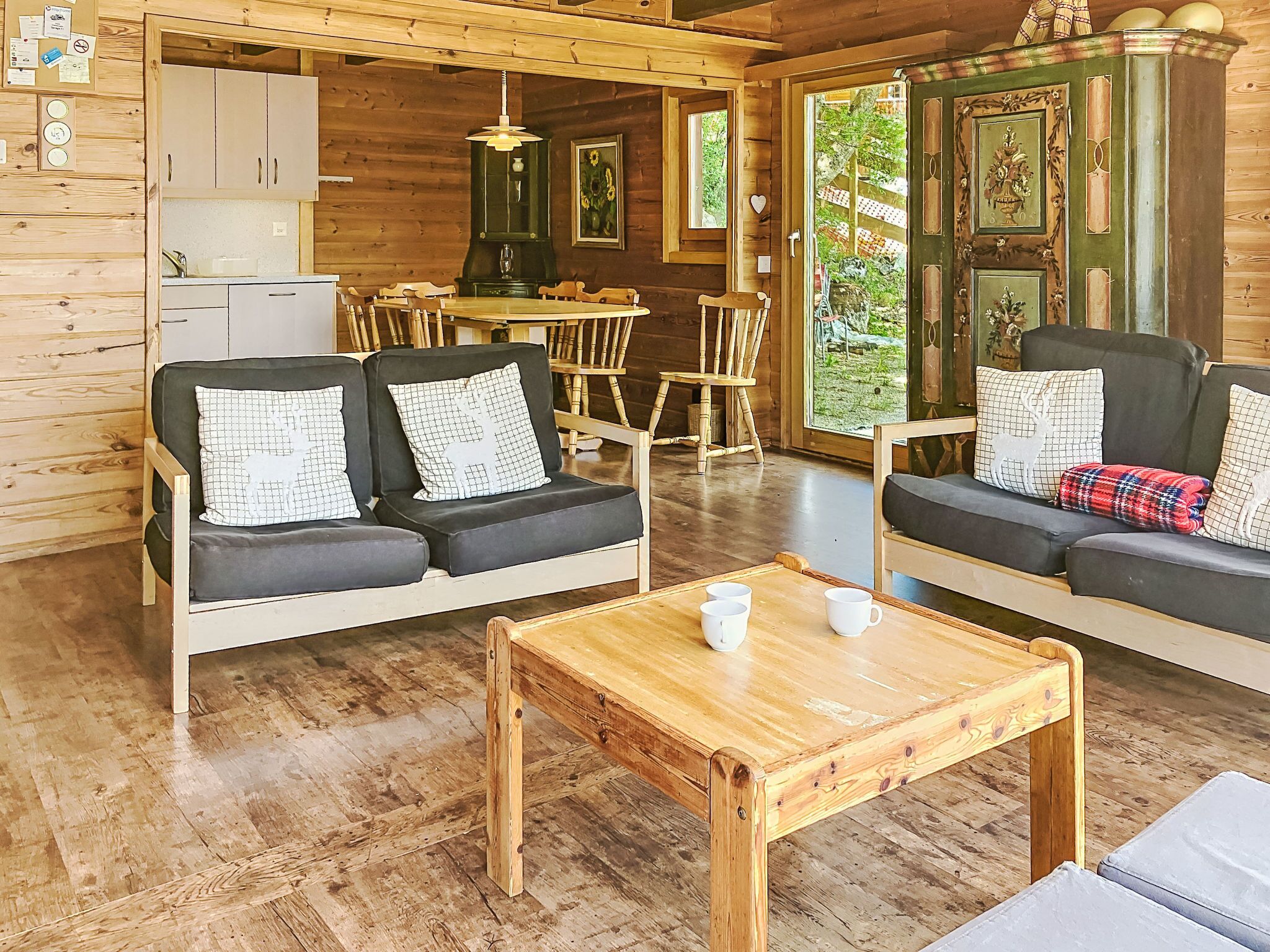 Interior acollidor d'una cabana amb un terra de fusta, dos sofàs amb coixins estampats, una taula de centre de fusta i una zona de menjador amb taula i cadires.