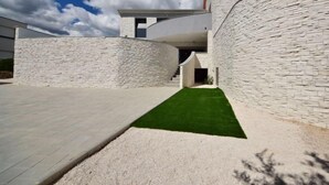 Un bâtiment moderne à la façade incurvée, doté d’une allée pavée et d’une pelouse verdoyante.
