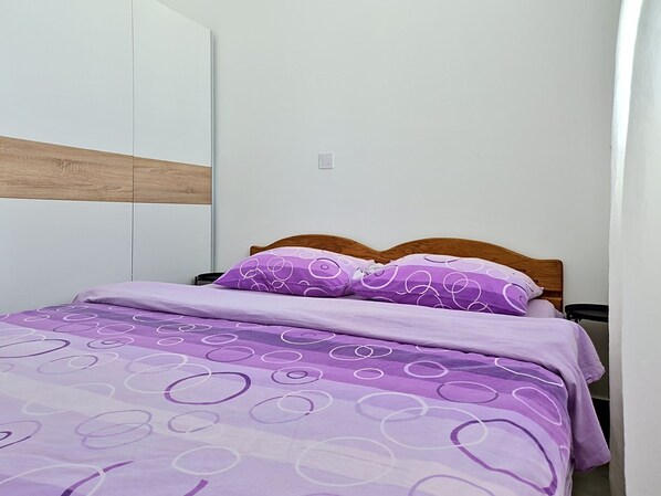 A bedroom with a bed, a wooden headboard, and a white wardrobe.
