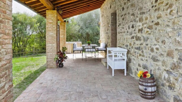Un patio couvert avec des murs en pierre, un sol en briques et du mobilier d’extérieur.