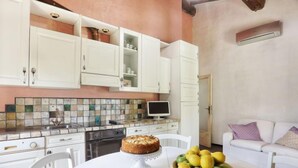 Une cuisine avec des meubles blancs, un pare-feu en carrelage et un coin repas comprenant une table et des chaises blanches.