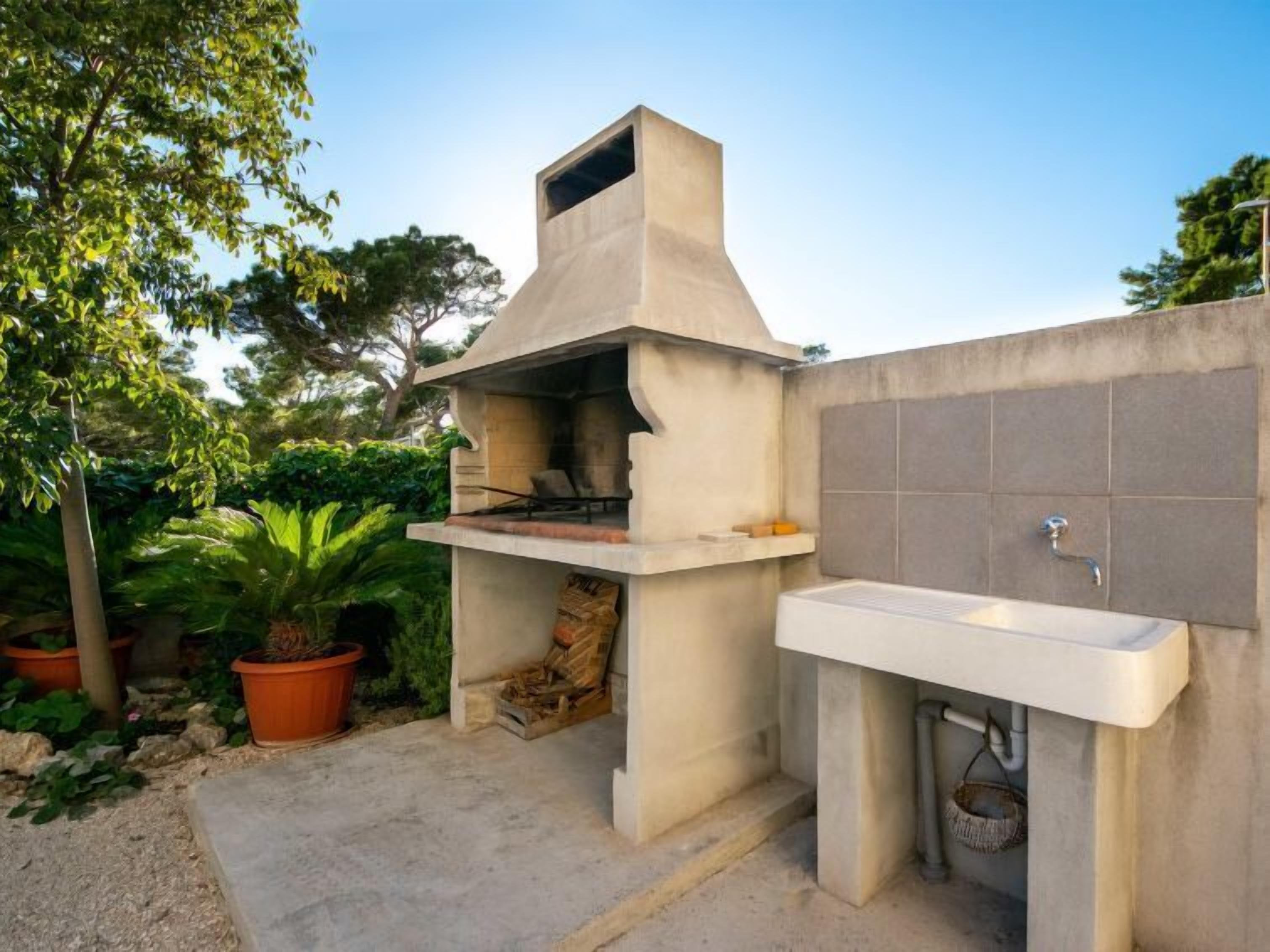 An outdoor kitchen with a concrete structure, a sink, and potted plants.