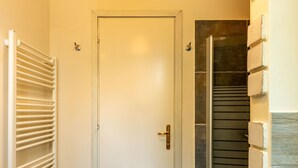 A door with a brass handle, a white radiator, and a stone wall with a textured pattern.
