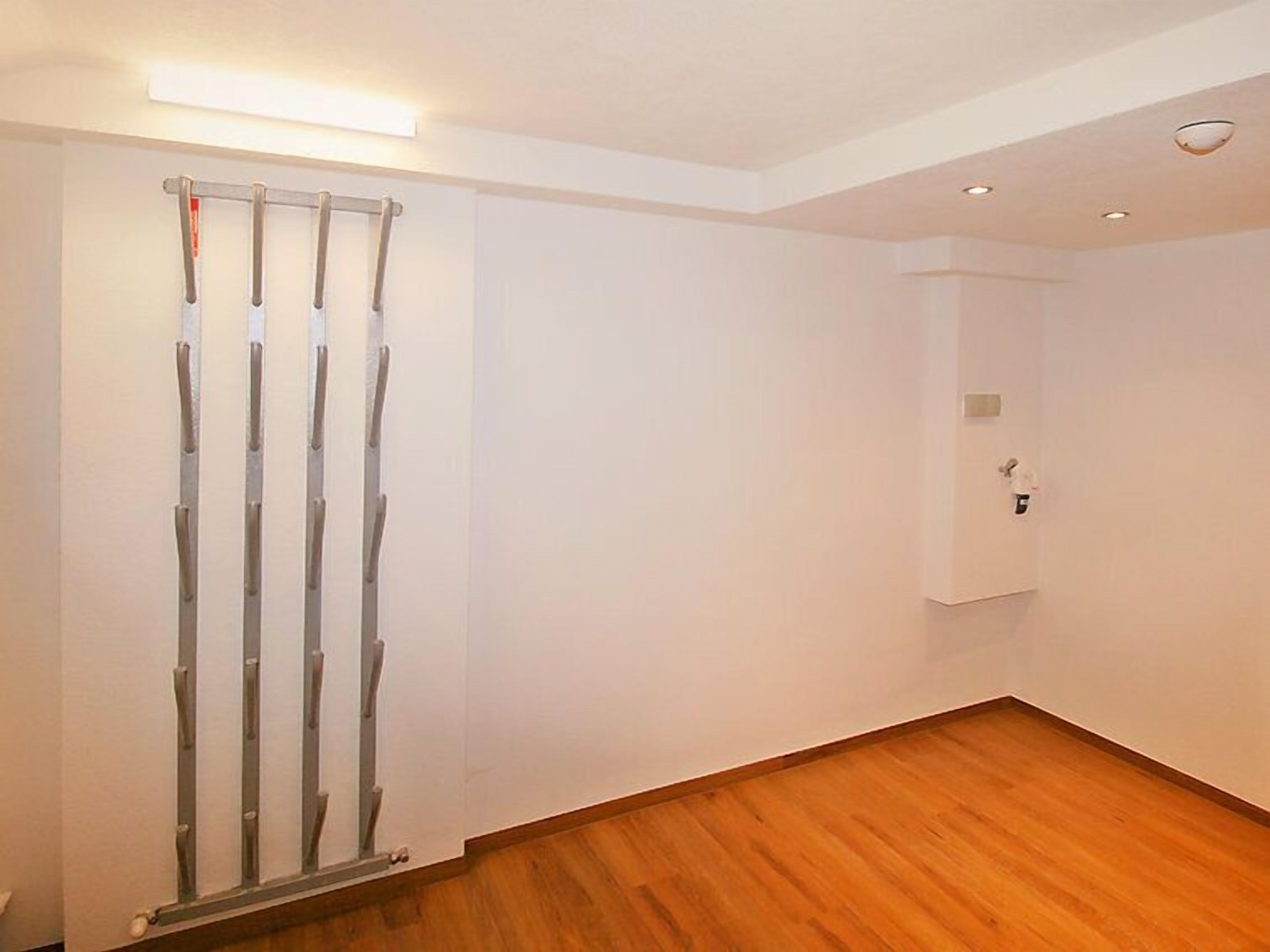 A room with a wooden floor, white walls, and a ceiling light.