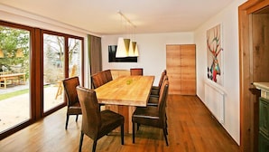 Een moderne eetruimte met een grote houten tafel, comfortabele stoelen en hanglampen.
