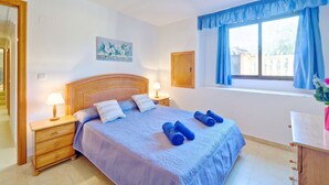 A bedroom with a bed, two bedside tables, a nightstand, a window with curtains, a wall-mounted light fixture, and a painting. - Apartment Raquel by Interhome (Calpe/Calp)