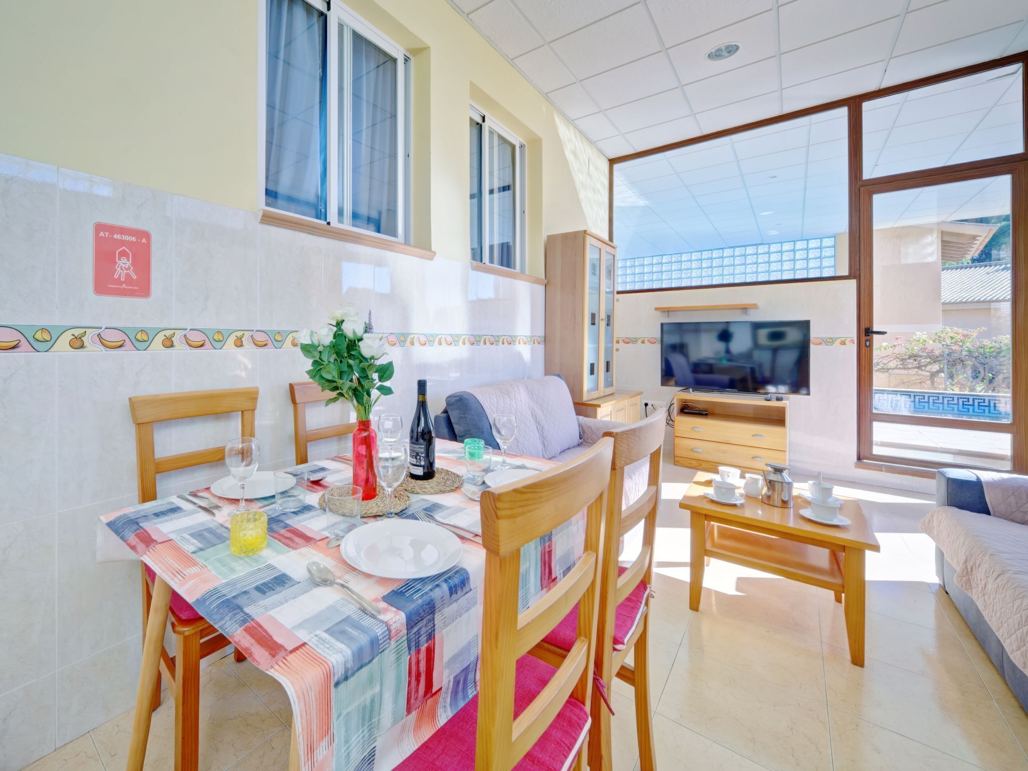 A dining area with a table set for two, a sofa, and a TV in the background.