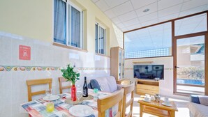 A dining area with a table set for two, a sofa, and a TV in the background. - Apartment Raquel by Interhome (Calpe/Calp)